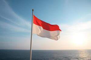 Indonesia national flag waving in the blue sky on the ocean background. Red and white flag with clouds. photo