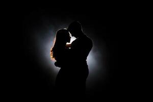 Silhouette of a romantic couple dancing and enjoying in the dark. photo