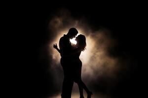 Silhouette of a romantic couple dancing and enjoying in the dark. photo