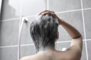 Woman washing hair with shampoo and shower in the bathroom. photo