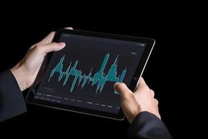 Business person analyzing stock market data on tablet with dark background. photo