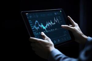 Business person analyzing stock market data on tablet with dark background. photo