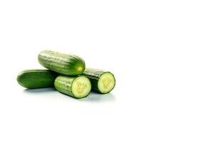 A pile of fresh whole and sliced green cucumbers isolated on white background with copy space. photo