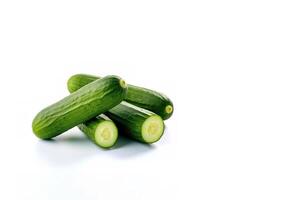 A pile of fresh whole and sliced green cucumbers isolated on white background. photo