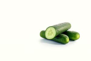 A pile of fresh whole and sliced green cucumbers isolated on white background with copy space. photo