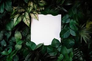 White paper card on lay green leaves texture top view background. Creative layout in nature concept. photo