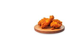 Crispy delicious fried chicken on a round wooden board isolated on white background with copy space. photo