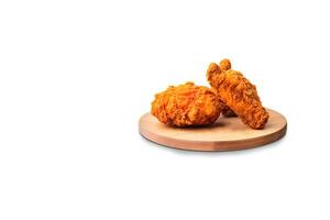 Crispy delicious fried chicken on a round wooden board isolated on white background with copy space. photo