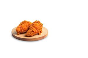 Crispy delicious fried chicken on a round wooden board isolated on white background with copy space. photo