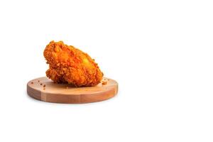 Crispy delicious fried chicken on a round wooden board isolated on white background with copy space. photo