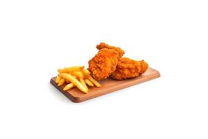 Crispy delicious fried chicken and french fries on a rectangular wooden board isolated on white background. photo