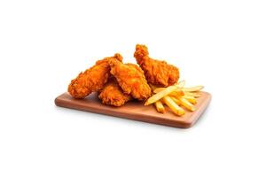 Crispy delicious fried chicken and french fries with sauce on a rectangular wooden board isolated on white background. photo