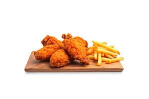 Crispy delicious fried chicken and french fries with sauce on a rectangular wooden board isolated on white background. photo