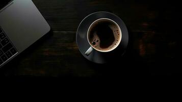 Laptop and coffee cup on black background. Top view with copy space photo