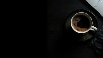 Laptop and coffee cup on black background. Top view with copy space photo