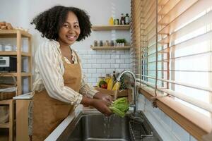 el ama de casa afroamericana está limpiando lechuga verde para preparar una ensalada simple y fácil de estilo sureño para el concepto de comida vegana y vegetariana foto