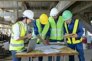 equipo de ingeniero, arquitecto, contratista y capataz reunión y consultante a construcción edificio sitio con piso plan para real inmuebles desarrollo proyecto industria y alojamiento cronograma foto