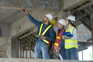 equipo de ingeniero, arquitecto, contratista y capataz reunión y consultante en construcción edificio sitio para inspección en real inmuebles desarrollo proyecto industria y especificación calidad controlar foto