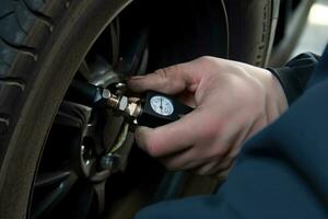 Rear view young mechanic checking tire pressure sensor with special tool photo