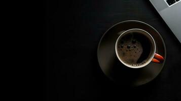 Laptop and coffee cup on black background. Top view with copy space photo