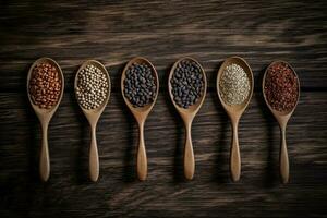 Assortment of legumes in wooden spoons on wooden background. photo