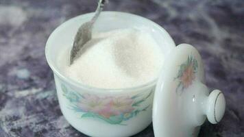white sugar and spoon in a container on black background video
