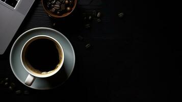 Laptop and coffee cup on black background. Top view with copy space photo