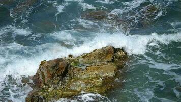 das Wellen von das Meer stürzt ab mit Macht auf das Felsen im schleppend moption video