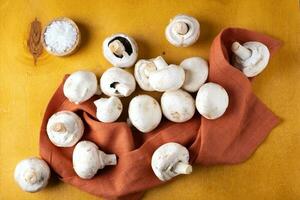 Champignon mushrooms on a linen napkin on a yellow background. photo