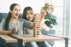 Young adult southeast asian couple relax lifestyle playing jenga board game at home photo