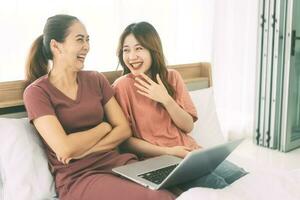 Two young adult woman living together with relationship laying at bedroom talking about work in the morning photo