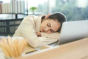 Young adult business asian woman fatique and sleep on table at office photo