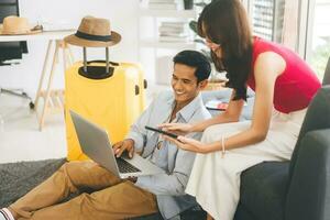 Young adult southeast asian couple using laptop for getting ready for holidays travel trip photo