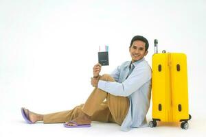 Portrait of young adult southeast asian man with yellow travel luggage and passport on white isolated background photo