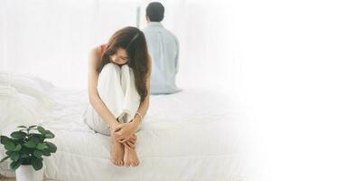 Woman hugged her knees sad and stress sitting on the bed about problem relationship banner size background photo