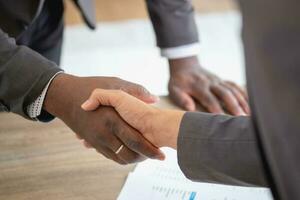 Satisfied black client shaking hands, thanking the manager for good financial deal African American businessmen shaking hands after successful business negotiations. Hiring. Buying services. photo