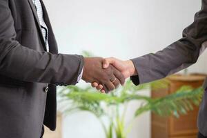 Satisfied black client shaking hands, thanking the manager for good financial deal African American businessmen shaking hands after successful business negotiations. Hiring. Buying services. photo