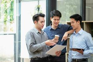 Asian business team consists of marketing staff. accountant and financial officer Help each other analyze company profits using tablets. calculator Laptop computers, graph paper, and corporate pens. photo