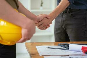 Asian engineers stand hand in hand to work together to document cost estimates and write floor plans for architectural and engineering designs for houses and buildings. photo