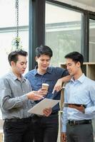 Asian business team consists of marketing staff. accountant and financial officer Help each other analyze company profits using tablets. calculator Laptop computers, graph paper, and corporate pens. photo