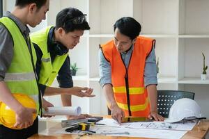 asiático ingenieros idea genial y medida a documento costo estimados y escribir piso planes para arquitectónico y Ingenieria diseños para casas y edificios foto