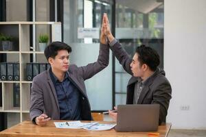 Portrait of an Asian business team showing great joy and happiness celebrating positive success in business concept. photo