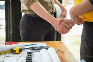 Asian engineers stand hand in hand to work together to document cost estimates and write floor plans for architectural and engineering designs for houses and buildings. photo