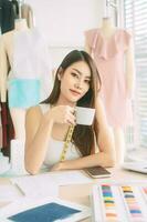 Vertical portrait young adult asian woman holding coffee cup in work place photo