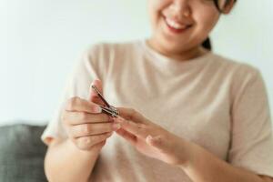 Woman cutting fingernails using nail clipper, Healthcare, Beauty Concept. photo