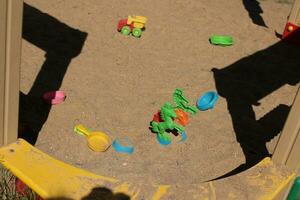 Plastic toys in the sandbox at the playground. Car, horse, saucer photo