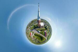 little planet transformation of spherical panorama 360 degrees overlooking church in center of globe in blue sky. Spherical abstract aerial view with curvature of space. photo