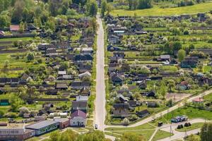 panoramic aerial view of eco village with wooden houses, gravel road, gardens and orchards photo