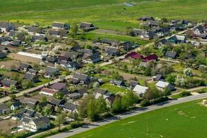 panoramic aerial view of eco village with wooden houses, gravel road, gardens and orchards photo