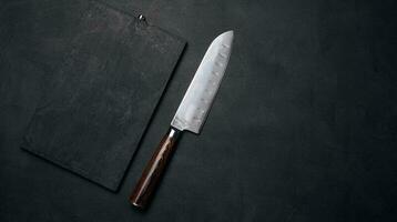 Empty black wooden cutting board and kitchen knife on black stoel, top view photo